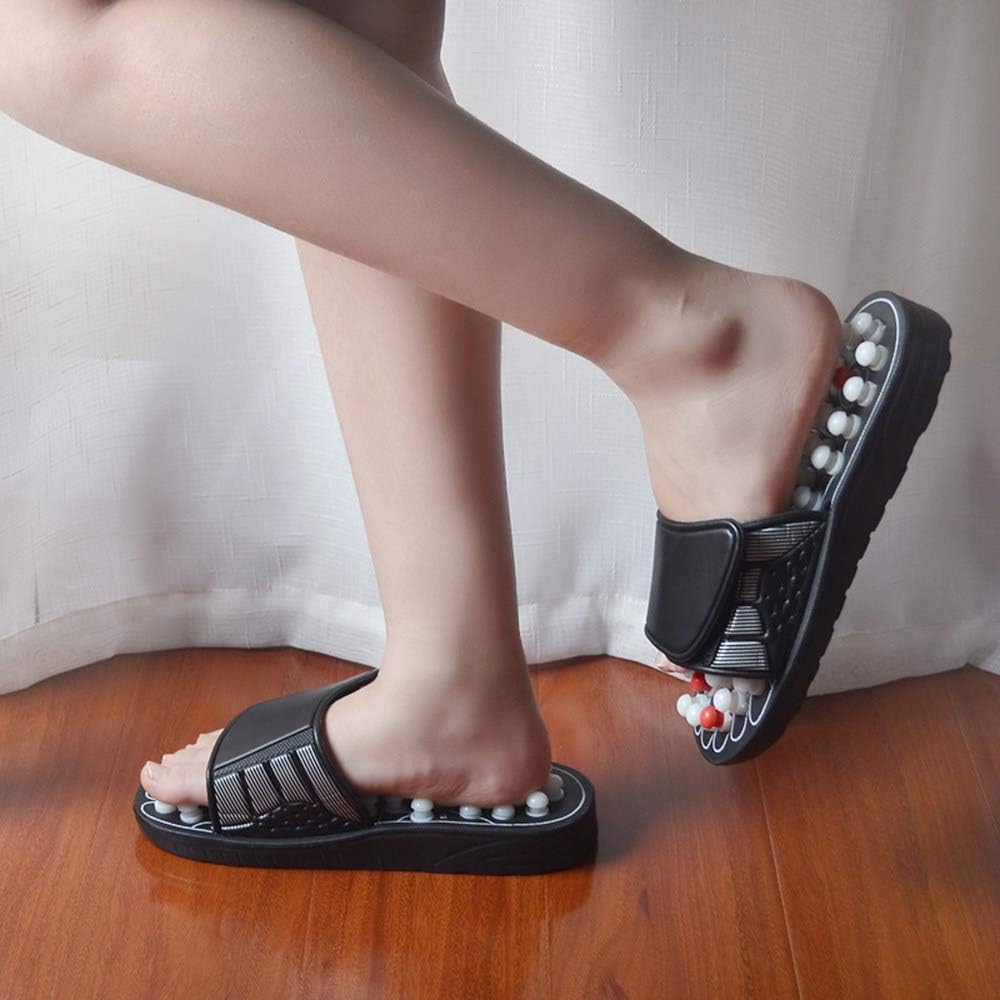 Person wearing acupressure massage sandals with adjustable black straps on wood floor