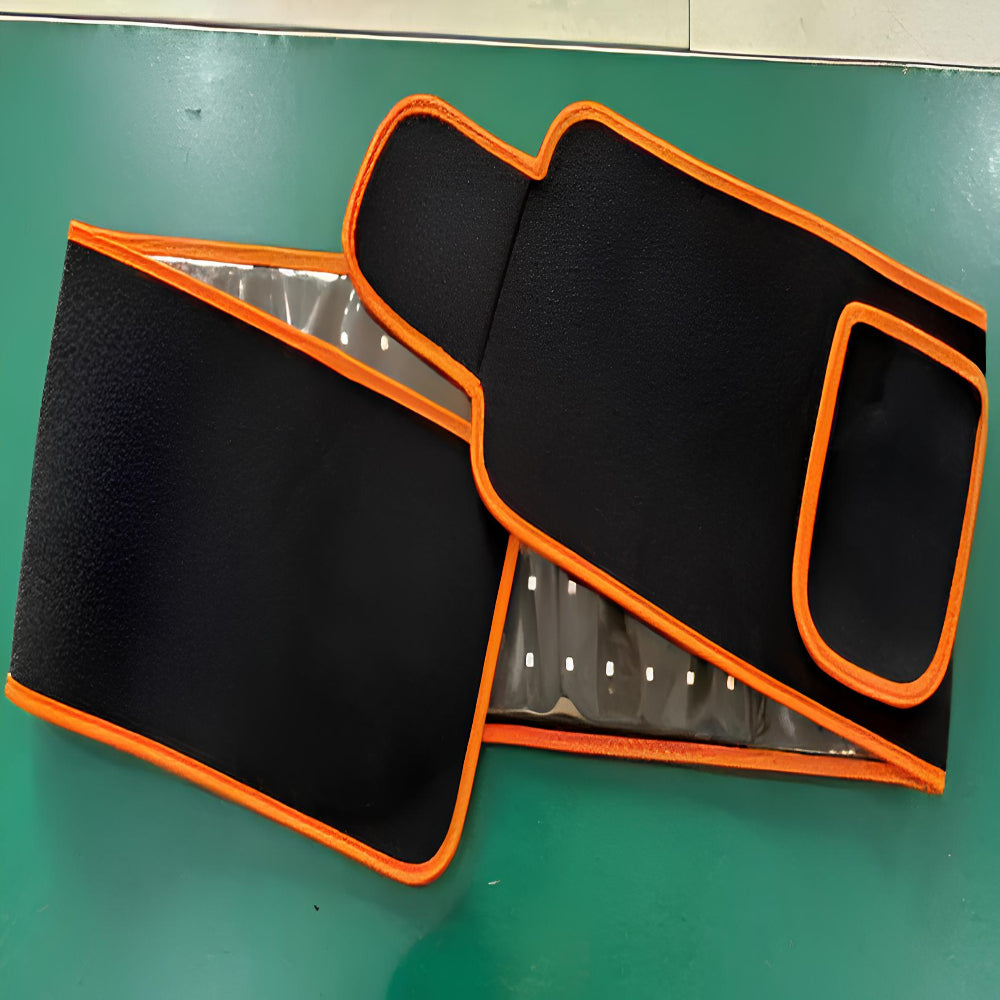 Black and orange heat therapy wrap for pain relief, displayed on a green surface